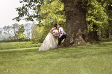 bride and groom kissing under a tree