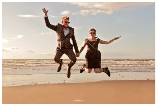 bride and groom jumping for joy on the beach