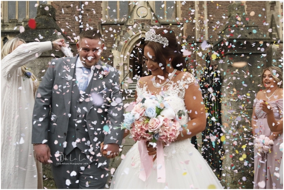 Bride and groom laughing in the confetti outside church