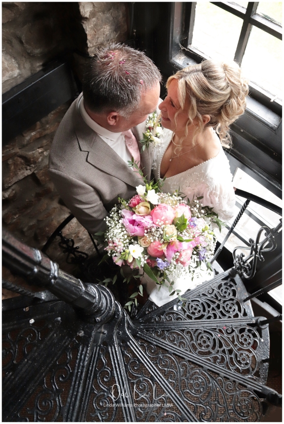 bride and groom smiling at each other on spiral staircase